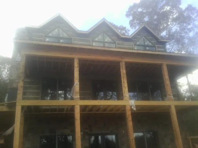 Dormers and porch framing on a large log home under construction — Roof Coating work by our crew in Hampstead