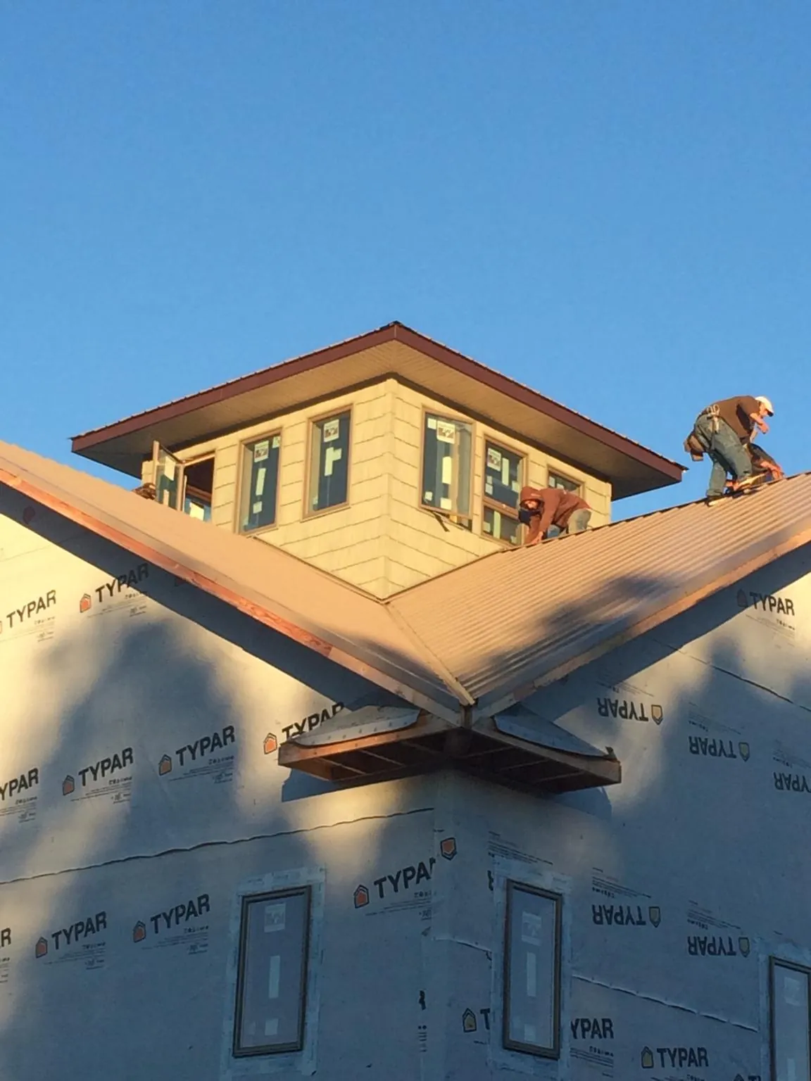 Roofers working around a rooftop cupola on a new metal roof at sunset — Roof Waterproofing in Hampstead by Roofing Brothers